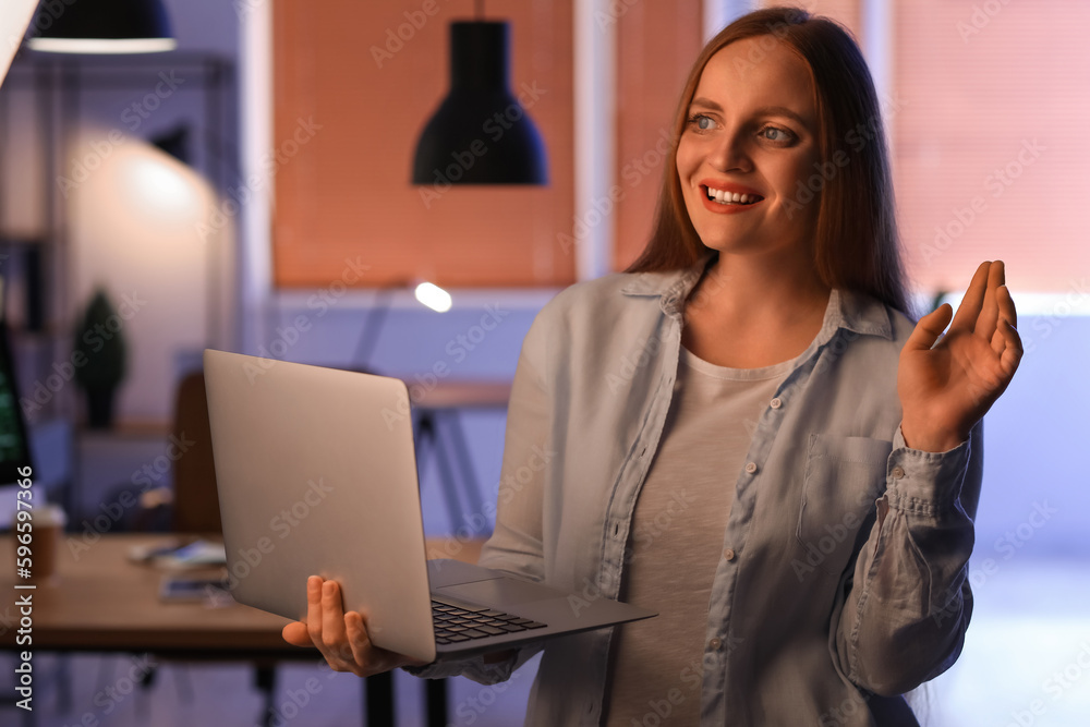 Female programmer working with laptop in office at night