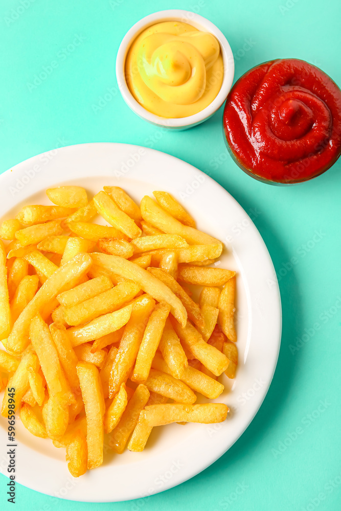 Plate of tasty french fries and sauces on color background, closeup