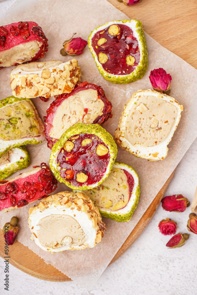 Wooden board with tasty Turkish Delight on light background, closeup