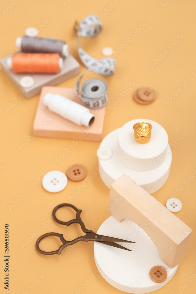 Podiums with tailors supplies on beige background, closeup