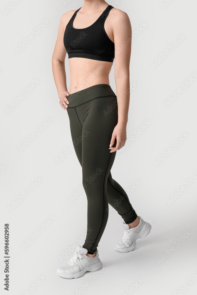 Sporty young woman in leggings on white background