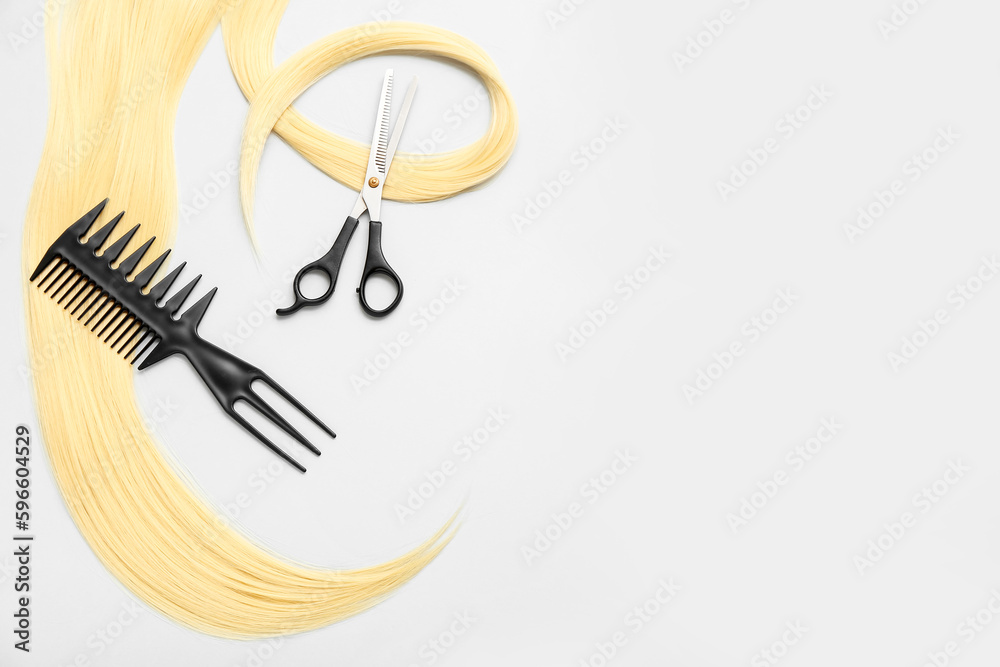 Hair strand with scissors and brush on white background