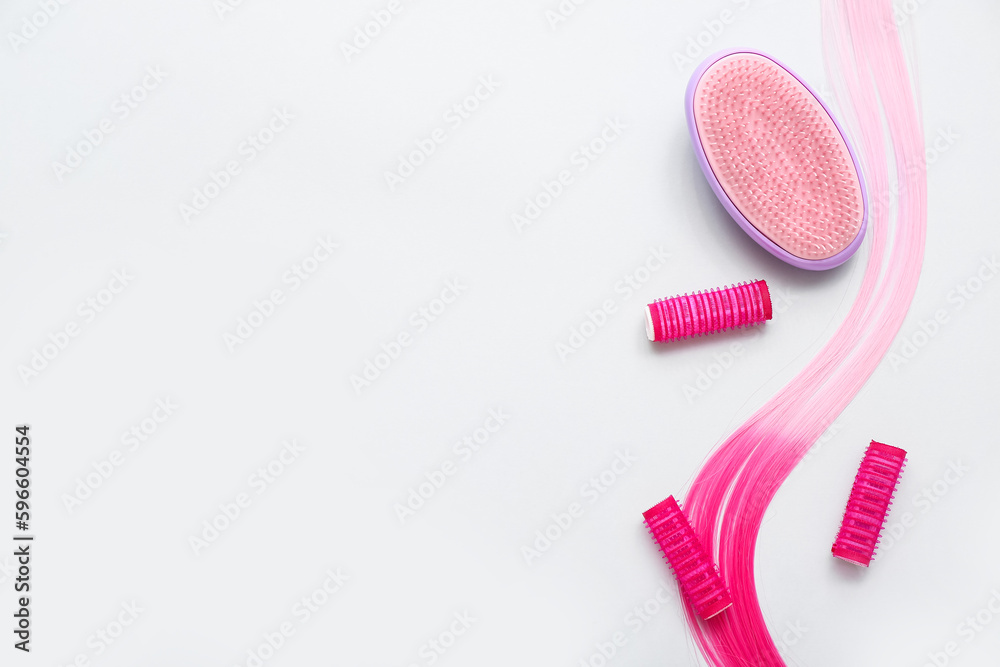 Pink hair strand with curlers and brush on white background