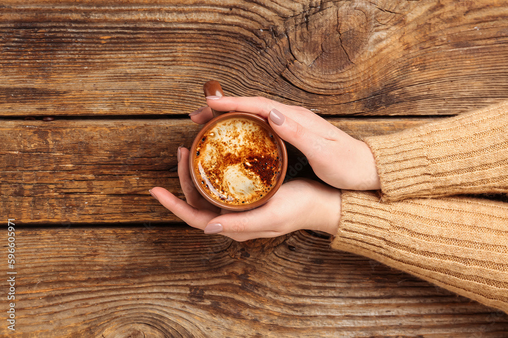 Woman with cup of coffee on wooden background