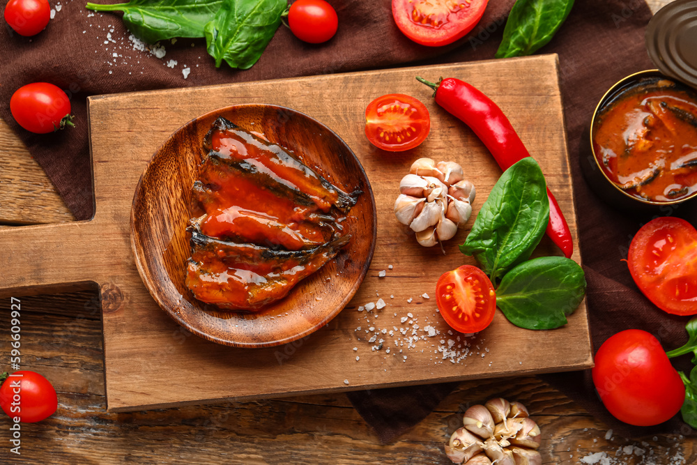 Composition with canned fish in tomato sauce and vegetables on wooden table