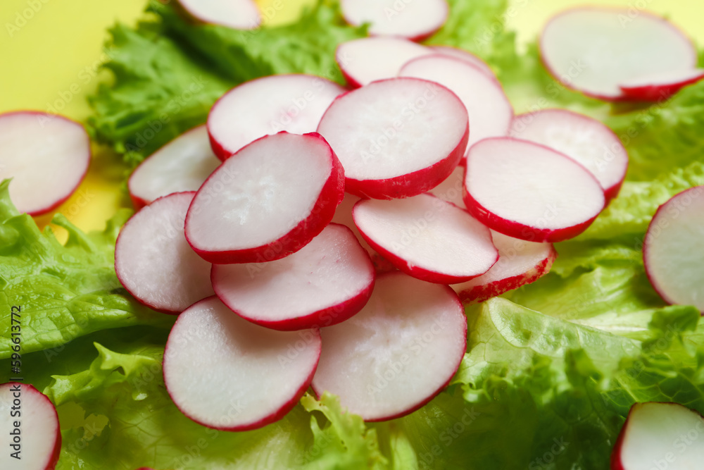 Lettuce and slices of fresh radish on yellow background, closeup