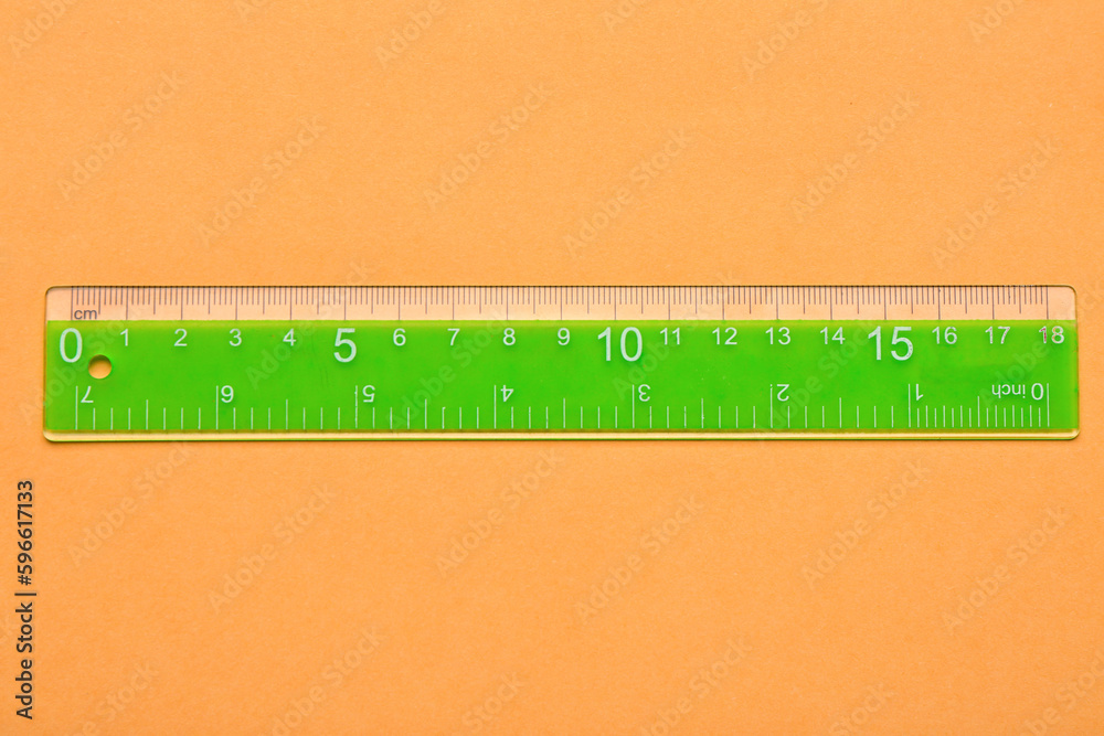 Green plastic ruler on orange background