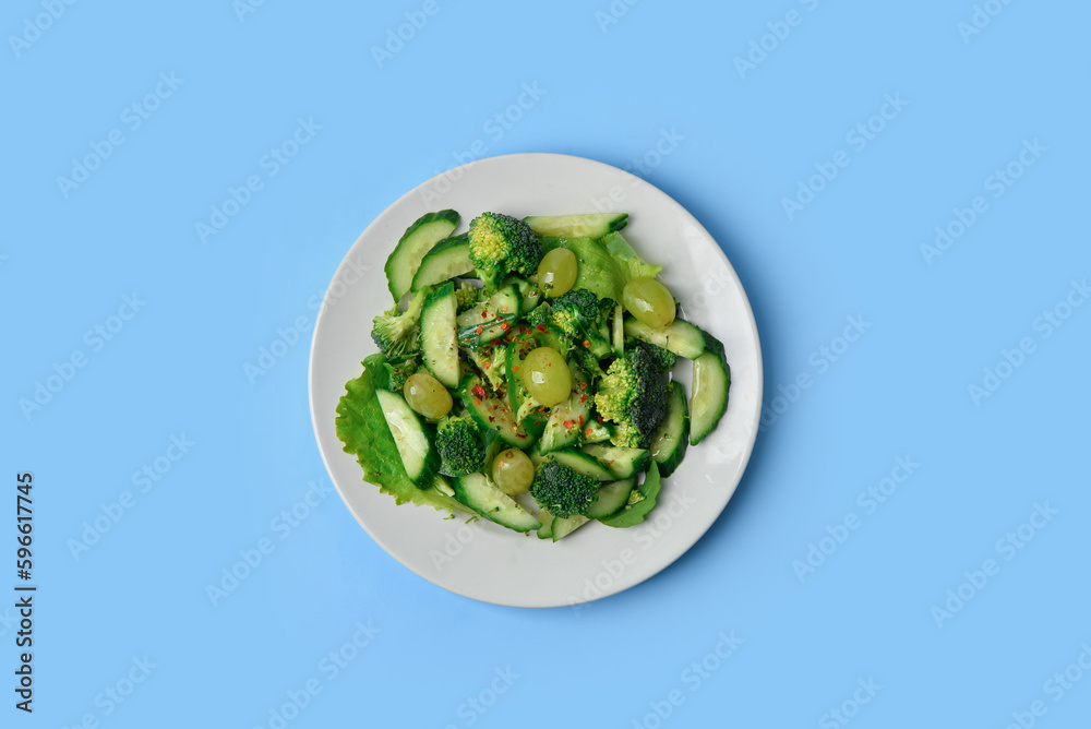 Plate with fresh salad on blue background