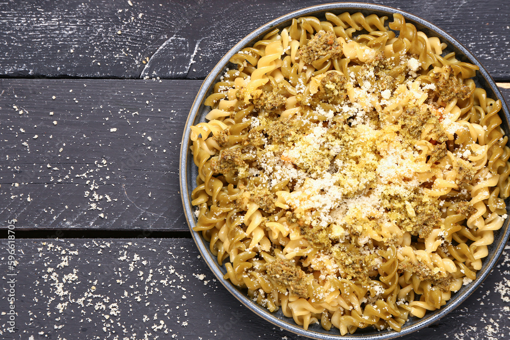 Plate of tasty Italian pasta with Parmesan cheese on dark wooden background