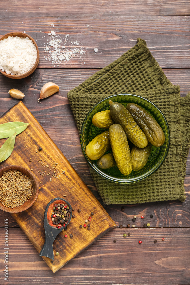 Bowl with tasty fermented cucumbers on wooden background