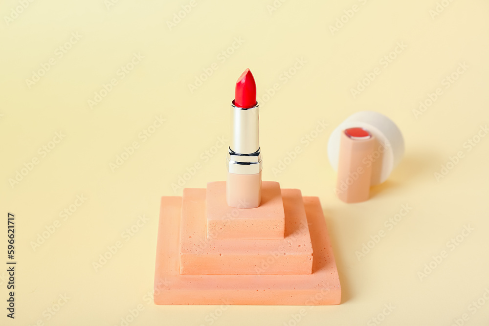 Decorative plaster podium and lipstick on yellow background