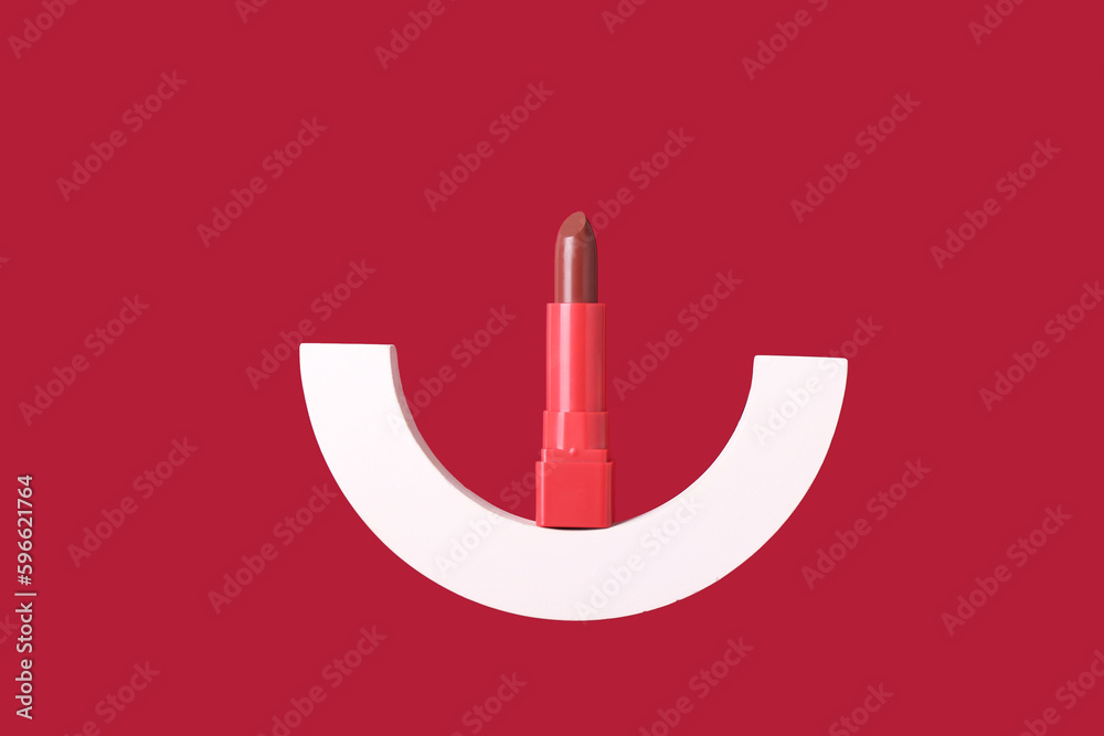 Decorative plaster podium and lipstick on red background