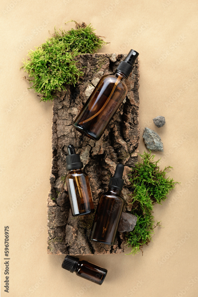 Unlabelled cosmetic bottles on natural beige background, natural moss over branches, bark. Skin care