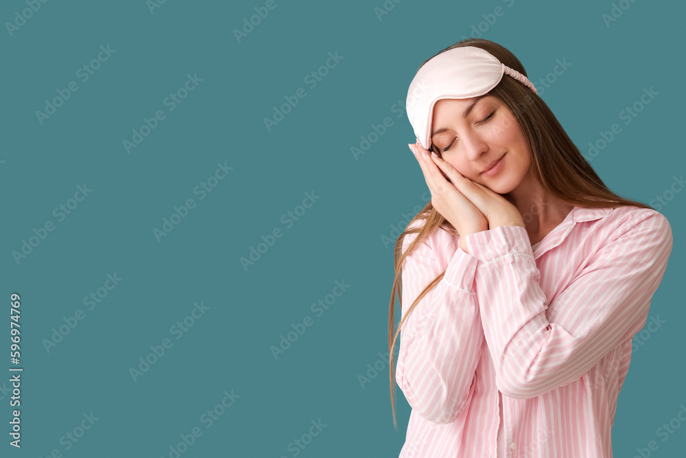 Young woman with sleeping mask on blue background