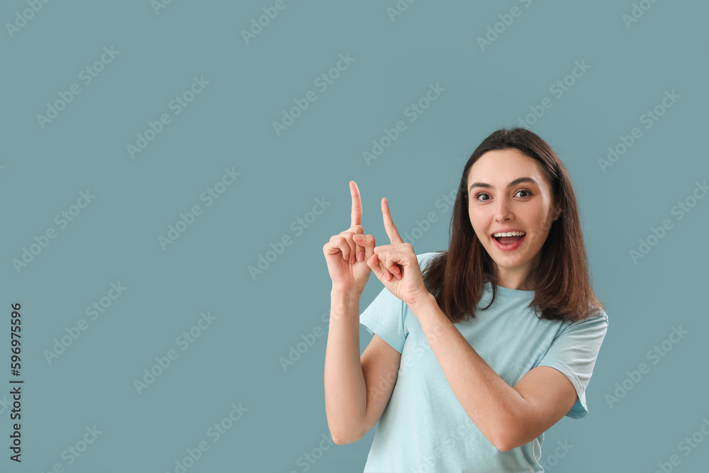 Young woman pointing at something on blue background