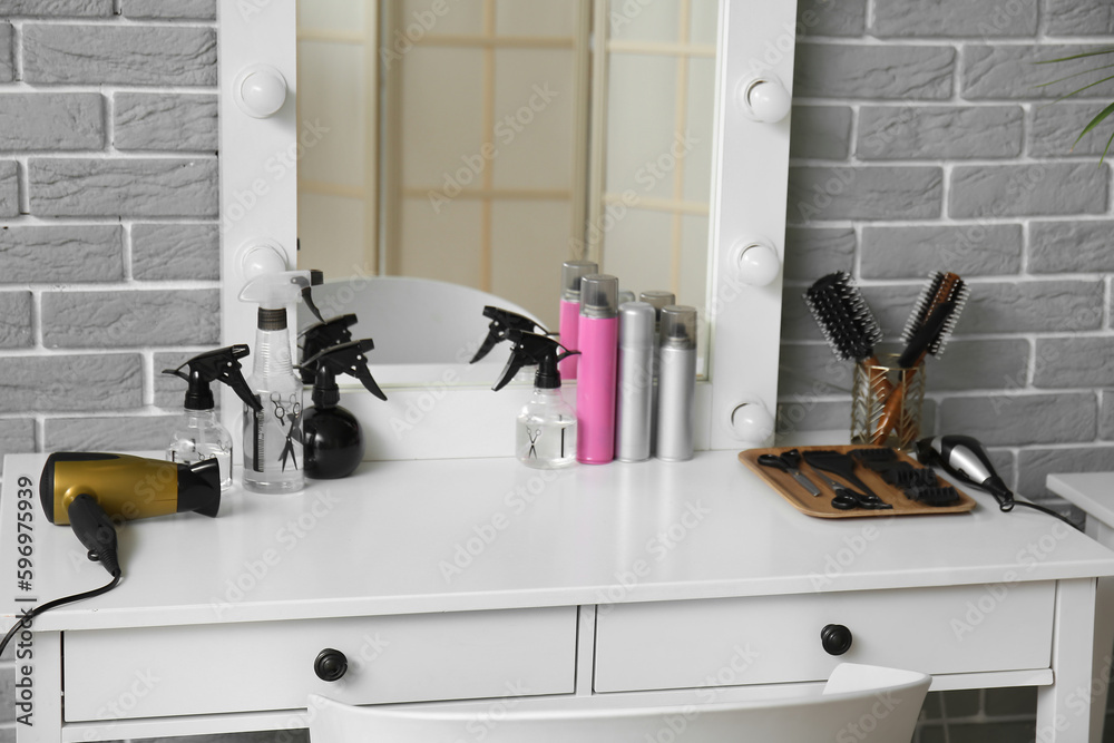 Different hair sprays and accessories on table in beauty salon