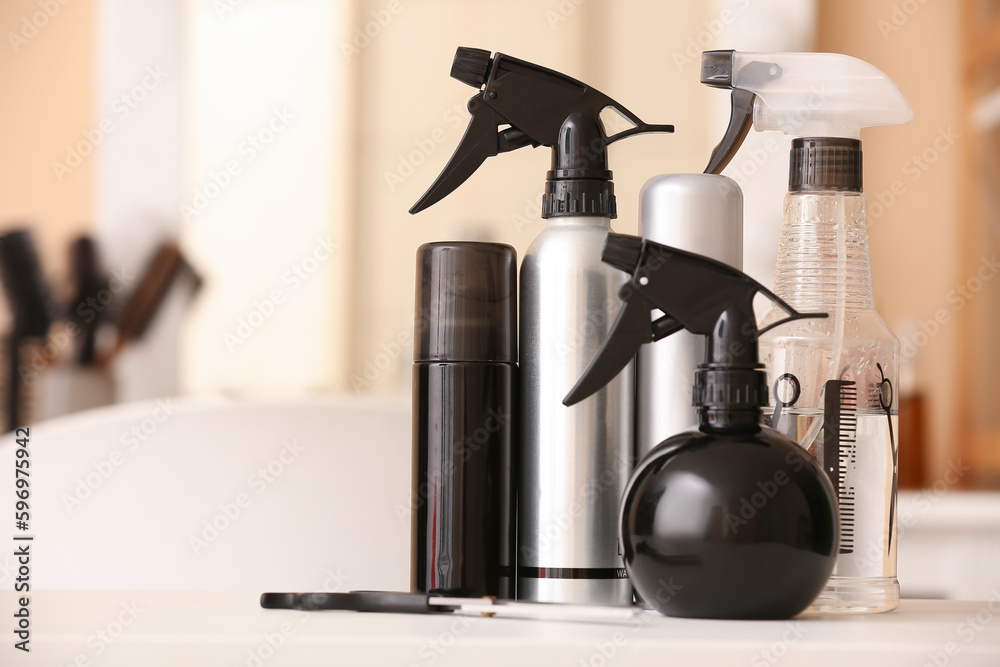 Different hair sprays on table in beauty salon