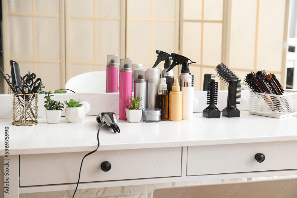 Different hair sprays and accessories on table in beauty salon