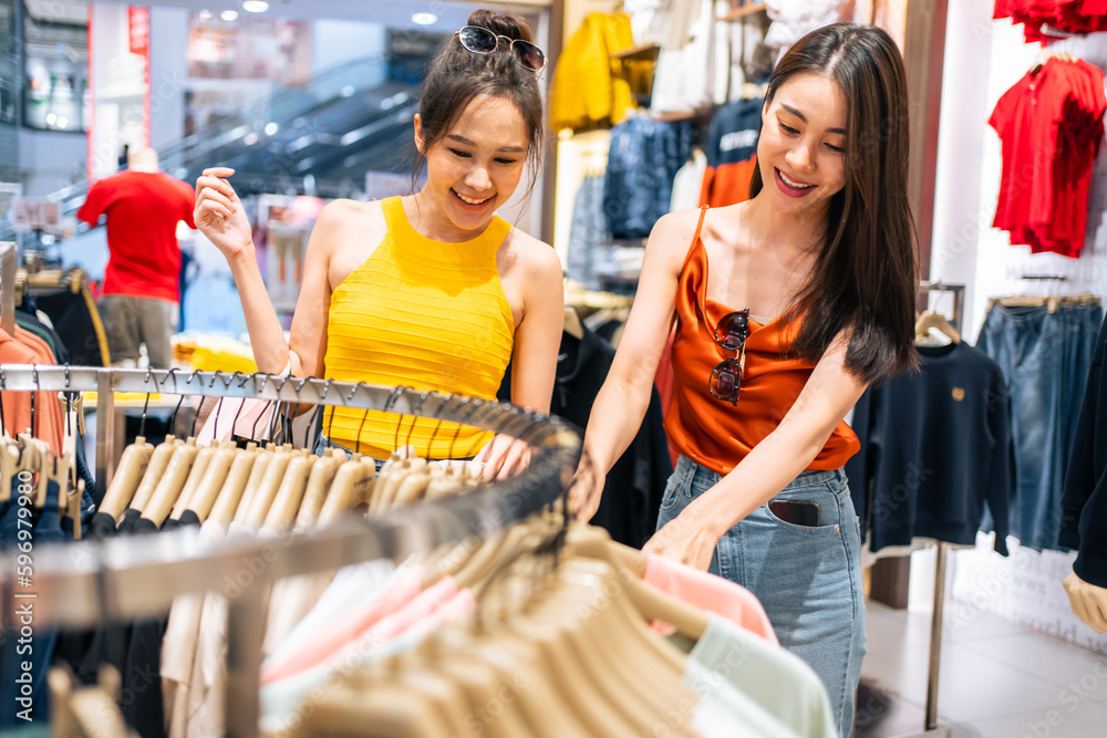 Asian two beautiful women looking at clothes product in shopping mall. 