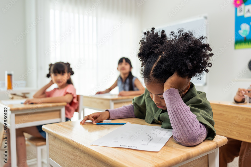 African American student doing exam in classroom at elementary school. 