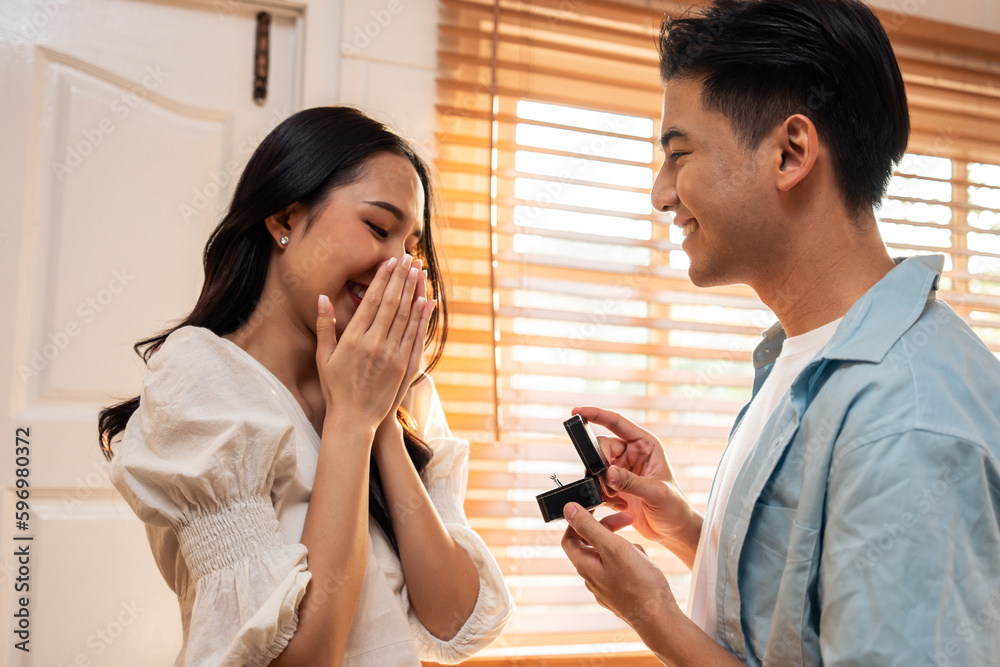 Asian romantic man making surprise proposal of marriage to girlfriend. 