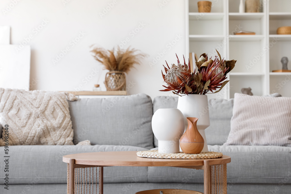 Cozy grey sofa and coffee table with bouquet of dried protea flowers in living room