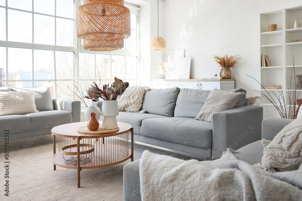 Cozy grey sofas and coffee table with bouquet of dried protea flowers in living room