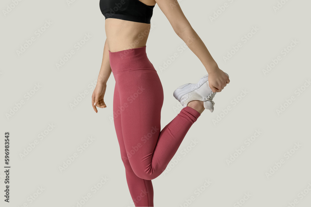 Sporty young woman in leggings on white background