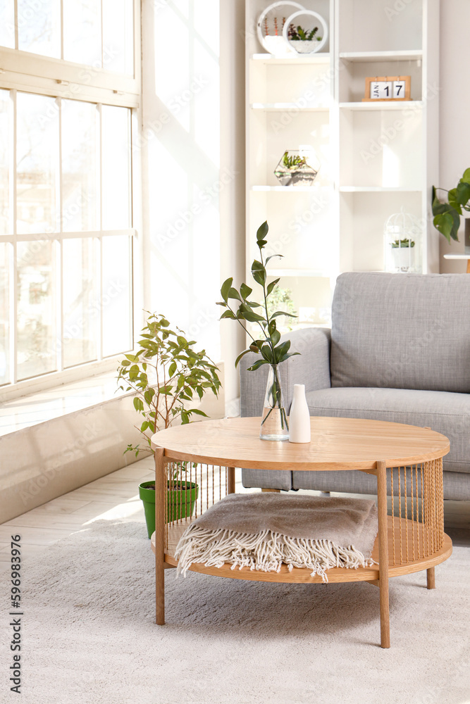 Vase with plant branches on coffee table in interior of bright living room