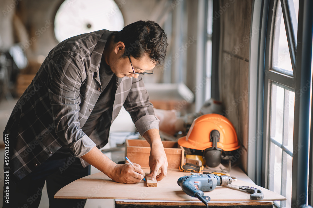 Asian carpenter working with equipment tools on wooden table in carpentry shop. Concept working of c