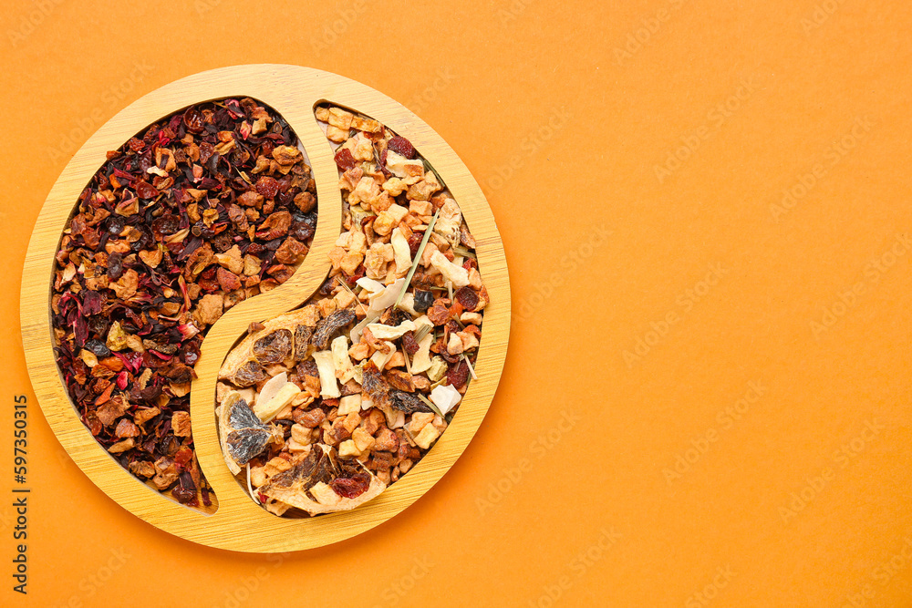 Wooden plate with dried fruit tea on orange background