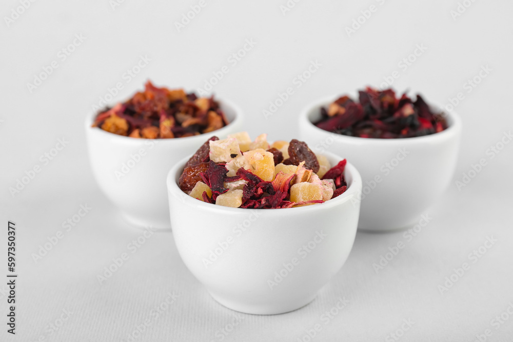 Bowls with different dried fruit tea on white background