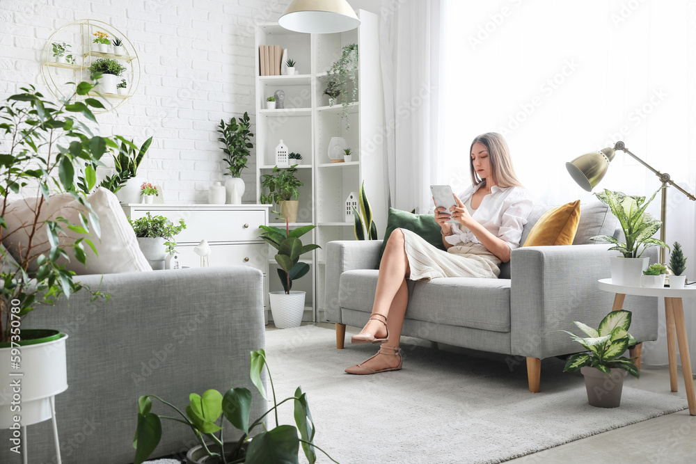 Young woman using tablet computer on sofa in living room