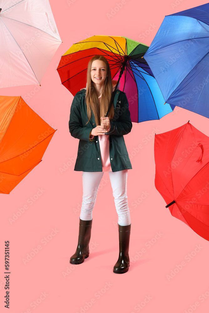 Teenage girl with umbrellas on pink background