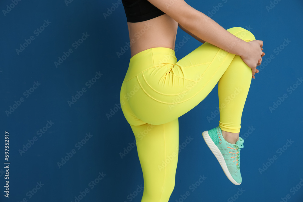 Sporty young woman in leggings on blue background