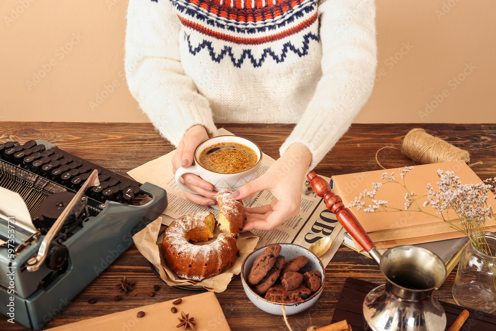 Woman with cup of coffee and cake at wooden table, closeup