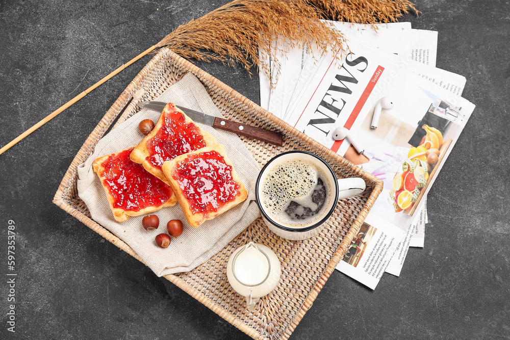 Tray with cup of coffee, milk, toasts and newspapers on dark background