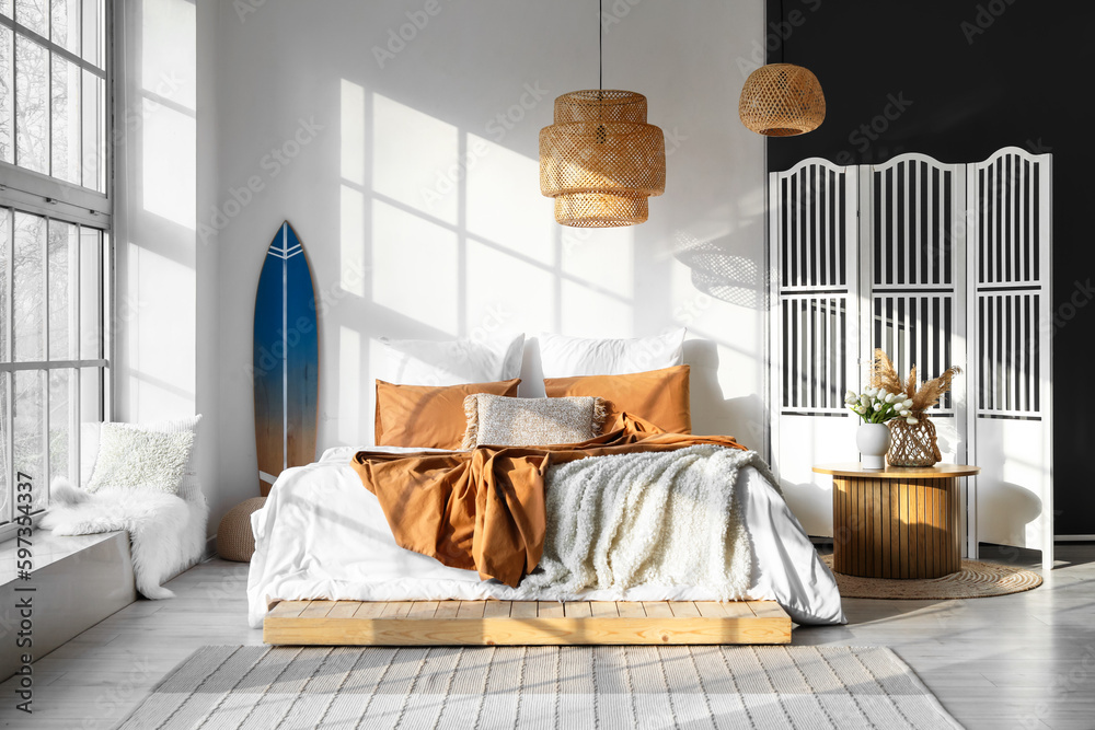 Interior of modern bedroom with surfboard and folding screen