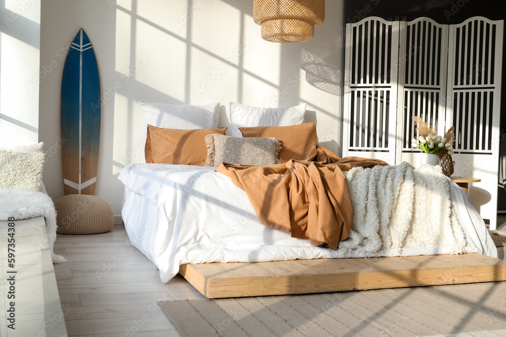 Interior of modern bedroom with surfboard and folding screen