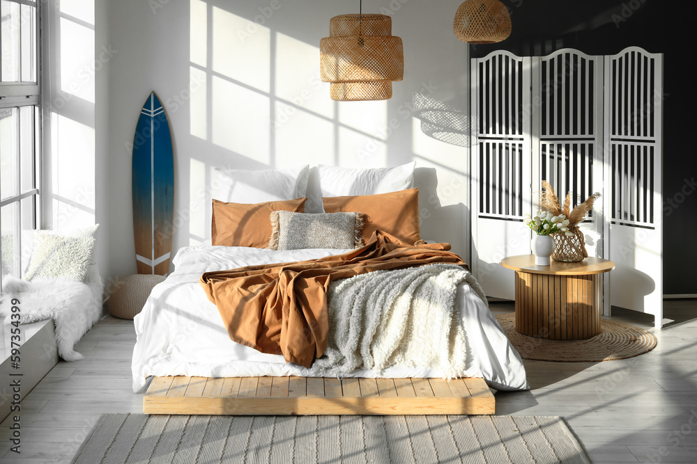 Interior of modern bedroom with surfboard and folding screen