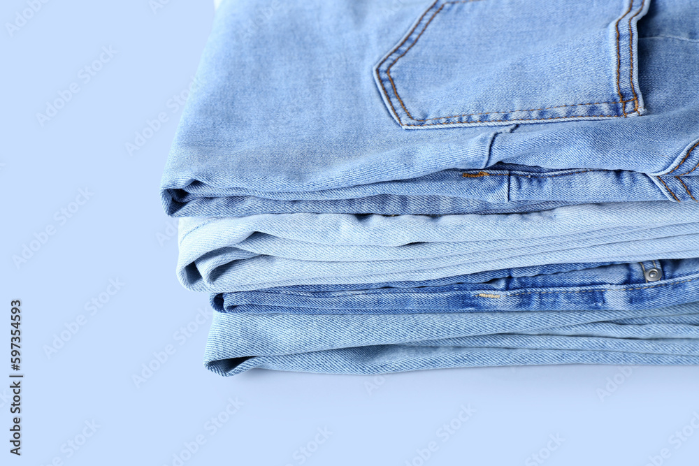 Stack of jeans on light background, closeup