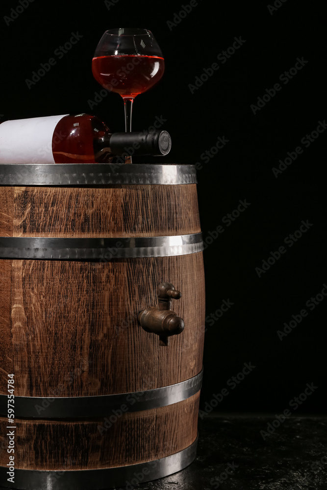 Wooden barrel with bottle and glass of wine on dark background