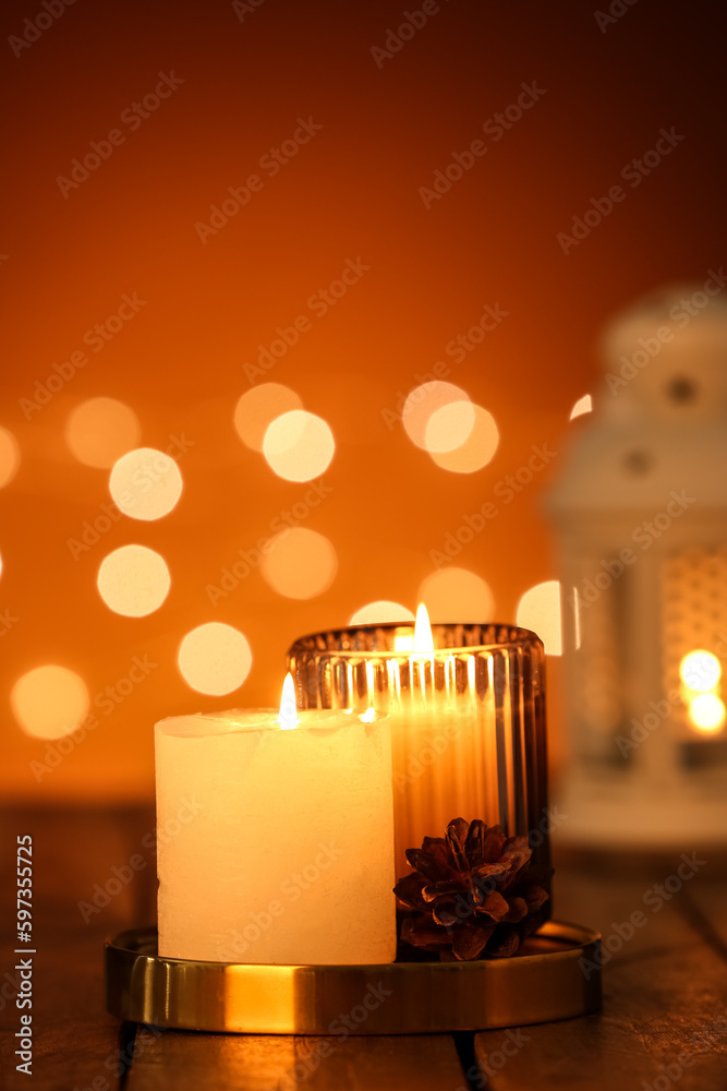 Burning candles on wooden table against blurred lights