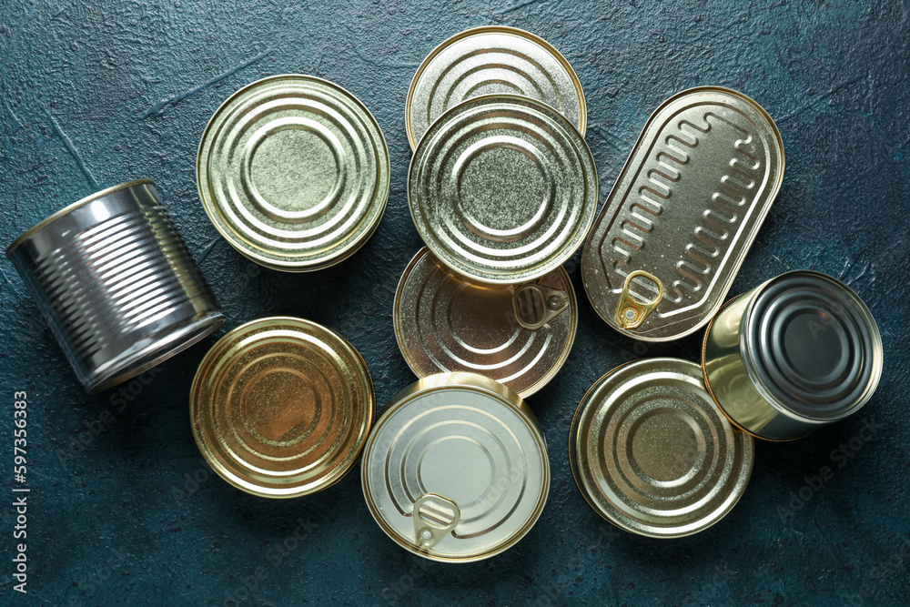 Assortment of tin cans with fish on dark table