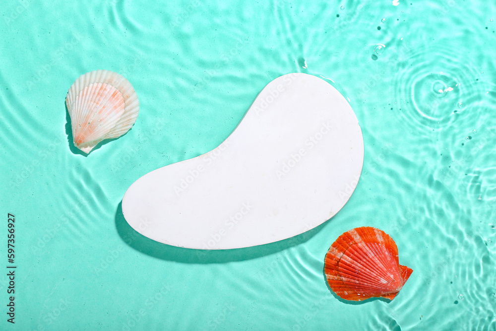 Decorative plaster podium and seashells in water on turquoise background