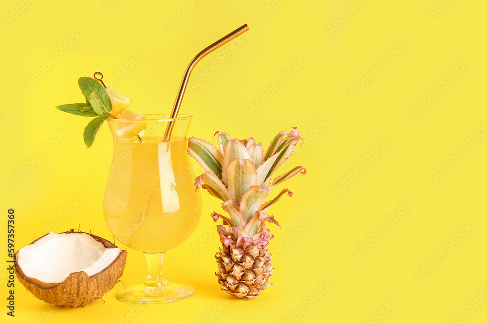 Glass of cocktail with baby pineapple and coconut on yellow background