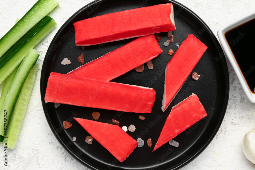 Plate with tasty crab sticks on light background