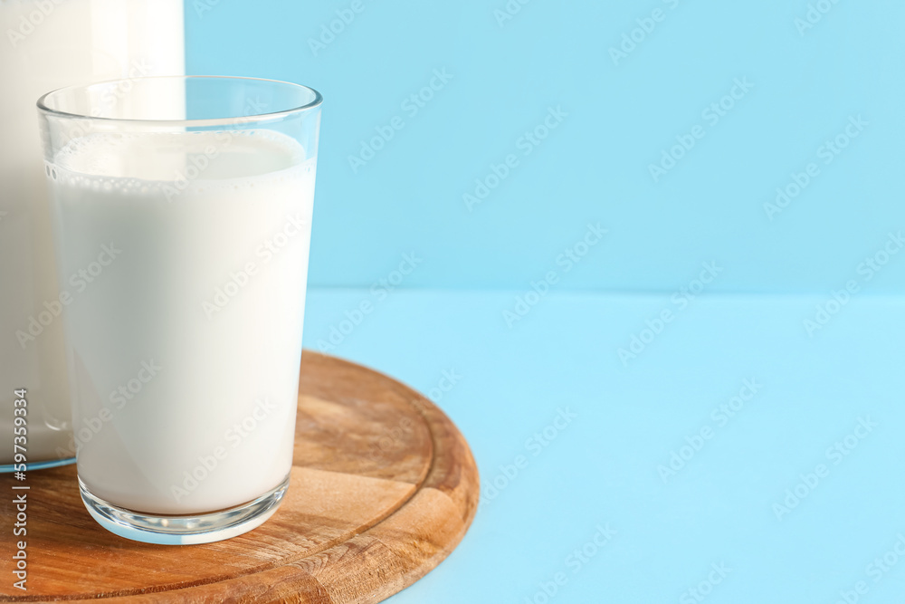 Jug and glass with fresh milk on blue background