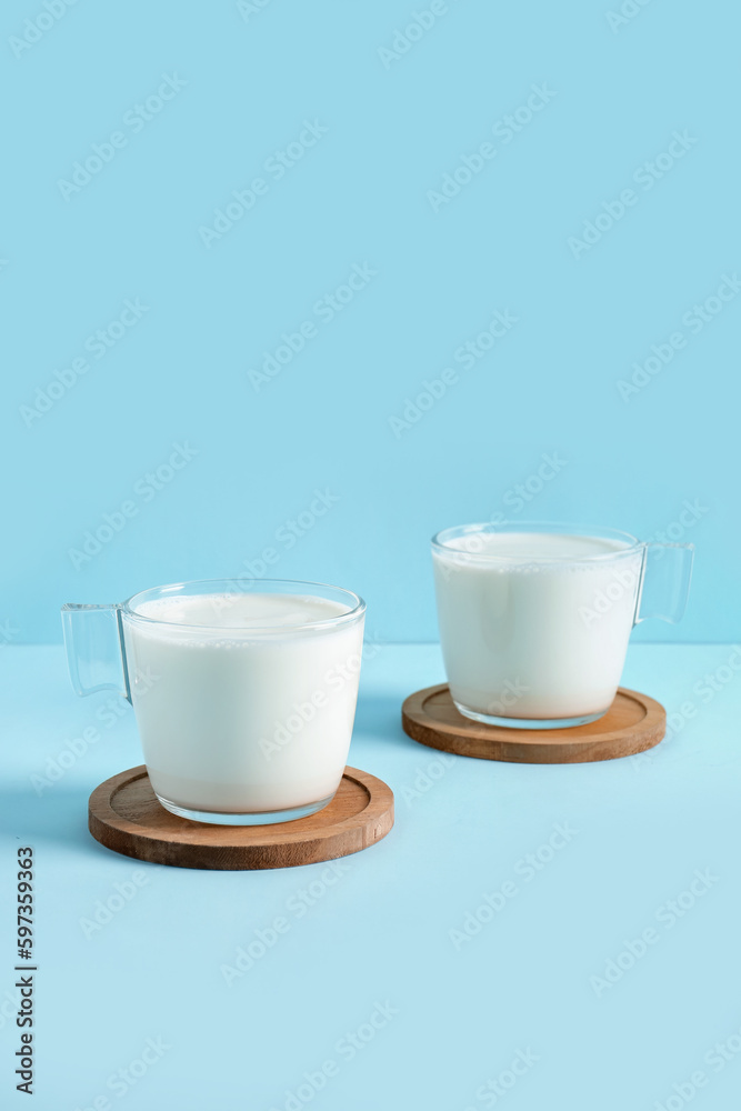 Glass cups with fresh milk on blue background