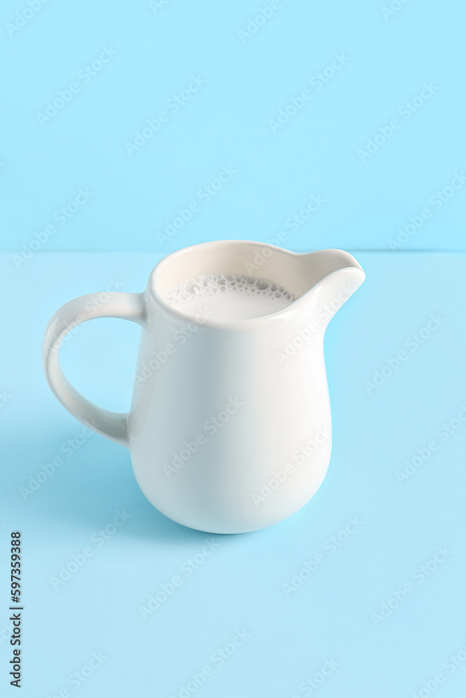 Jug with fresh milk on blue background